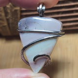 Pastel colored jasper pendant held between fingers