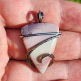 Pastel colored jasper pendant in sterling silver held in hand