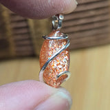 Close-up of a glittery pendant held between two fingers with a blurred background