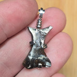 Metallic pendant held between fingers with a blurred background
