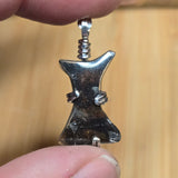 Pallasite Meteorite held between fingers against a wooden background