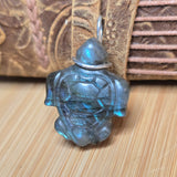 Turtle-shaped pendant with a metallic sheen on a wooden surface