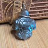 Turtle-shaped pendant with blue gemstone on a wooden surface