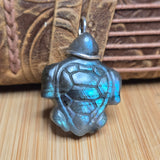 Turtle-shaped pendant with blue metallic sheen on a wooden surface