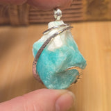 Turquoise crystal stone with silver ring on a wooden surface