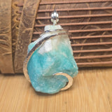 Amazonite Crystal stone with silver ring on a wooden surface
