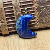 Blue stone crescent moon pendant on a wooden background