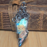 Silver pendant with a colorful stone on a wooden background