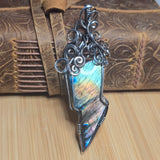 Decorative silver labradorite lightning bolt pendant on a wooden surface