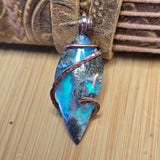 Aurora Opal pendant with blue and silver design on a wooden surface