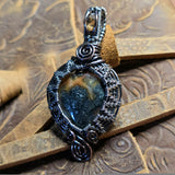 Silver pendant with a central stone on a textured wooden background