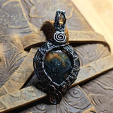 Black and silver wire-wrapped pendant on a textured stone surface