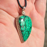 Plume malachite pendant on a cord held in a hand