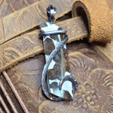 Silver pendant on a textured brown leather surface