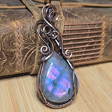 Ornate pendant with a colorful stone on a wooden surface
