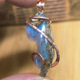 Jewelry pendant with blue stone and copper wire wrapping held between fingers.