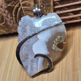 Agate pendant with silver wave design on a wooden surface