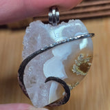 Silver pendant on a white stone with a wooden background