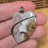 Crystal pendant held in a hand with a wooden background