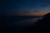 Dusk scene at a beach with dark blue sky and water.