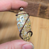 Hand holding a decorative object with floral pattern on a wooden surface