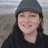  picture of Laura Jockey a woman and a hat wearing a wet sweatshirt on the beach in Oregon