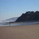 Person walking on a beach with a mountain in the background