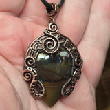 Decorative wire wrapped pendant with a Oregon Jellybean jasper stone held in a hand