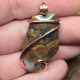 Pendant with a natural stone design held between fingers