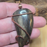 Hand holding a stone pendant with copper wire wrapping
