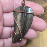 Hand holding a stone pendant with copper accents