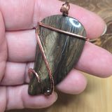 Hand holding a stone pendant with copper wire wrapping