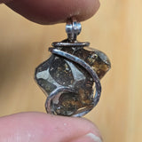 Close-up of a silver pallasite held between fingers with a blurred background