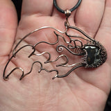 Hand holding a copper wire sculpture of a meteor against a natural background