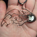 Hand holding a copper wire sculpture of a meteor against a natural background