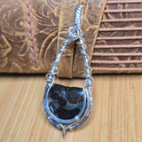 Silver pendant with Pallasite on a wooden surface