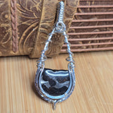Silver pendant with a Pallasite stone on a wooden surface