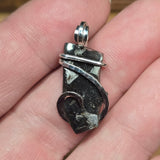 Silver pendant with black stone held in a hand
