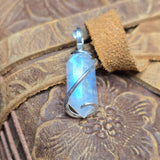 Rainbow Moonstone pendant on a leather surface with floral embossing