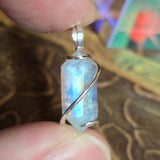 Moonstone pendant held between fingers with a blurred background