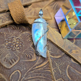 Rainbow Moonstone pendant on a textured brown surface