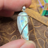 Moonstone pendant held between fingers with a patterned background