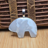 White bear-shaped pendant on a brown leather strap with a wooden surface background