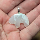 White stone pendant on a silver chain held in a hand