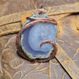 Geode pendant with copper wire wrapping on a textured fabric background