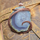 Copper-wrapped agate pendant on a textured brown background