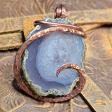Copper-wrapped agate pendant on a textured surface