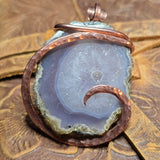 Agate pendant with copper wire wrapping on a wooden surface
