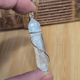 Crystal Pendant held between fingers on a wooden surface