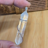 Crystal pendant held between fingers on a wooden background